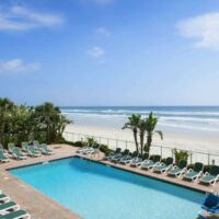 View of the outdoor pool, beach, and ocean from Days Inn by Wyndham in Daytona Beach