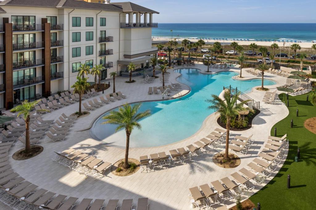 Aerial view of the outdoor pool, surrounded by chairs and palm trees, next to Embassy Suites by Hilton Panama City Beach Resort