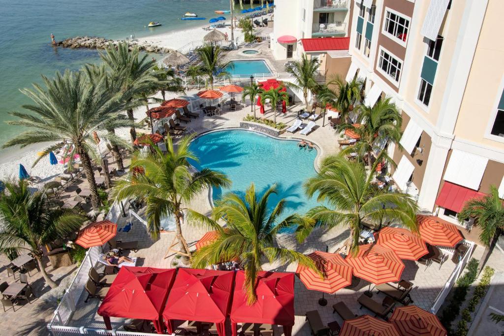 Aerial view of the outdoor pool surrounded by umbrellas and palm trees, at Hampton Inn and Suites Clearwater Beach in Florida