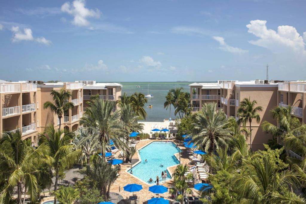 Aerial view of the outdoor pool facing the ocean and surrounded by umbrellas and trees at Key West Marriott Beachside Hotel in Key West