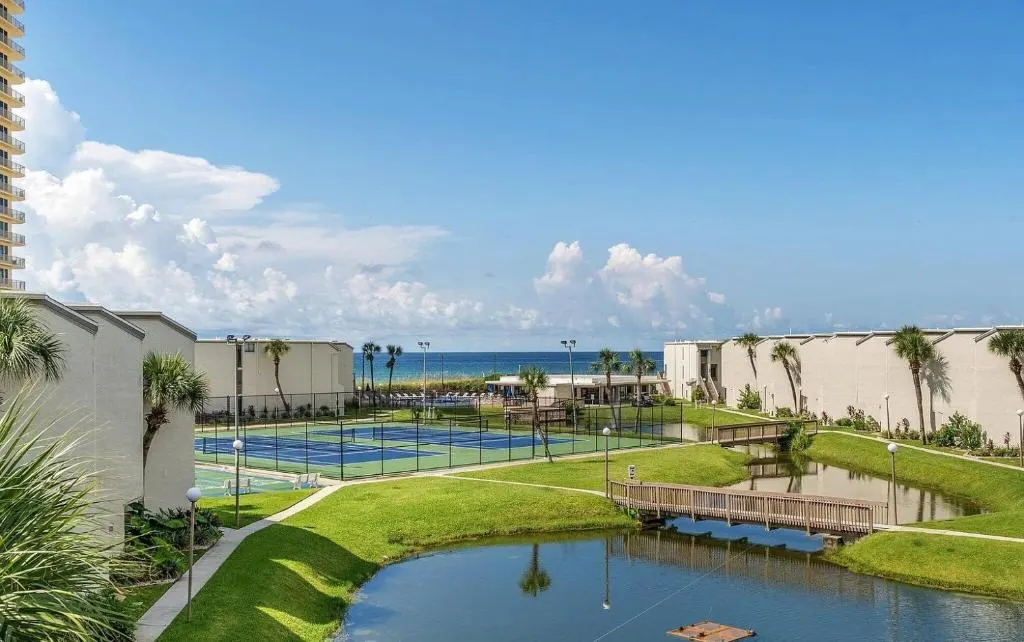 Aerial view of a pond, tennis courts, and condos at Sugar Beach Condo Resort in Panama City Beach